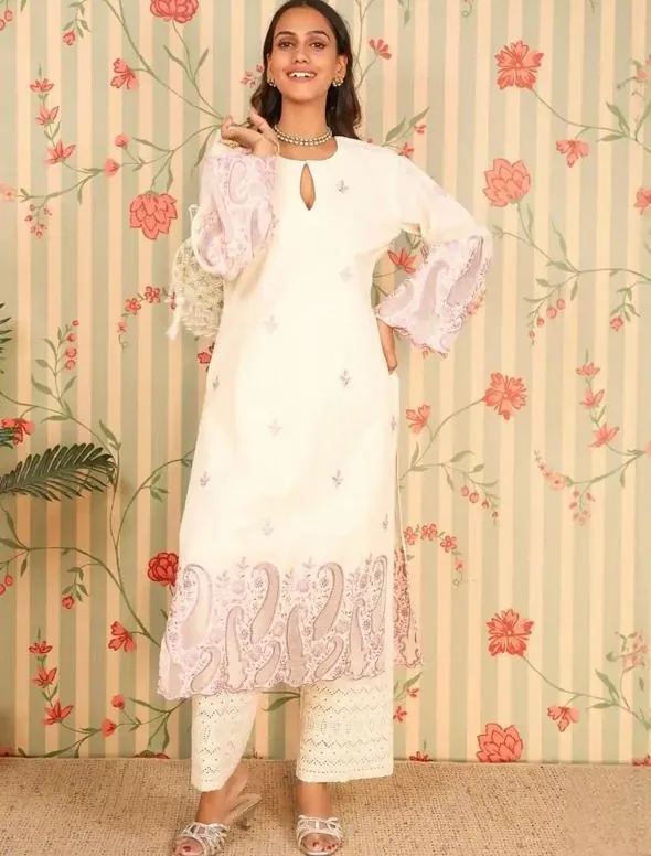 Aanchal in an ivory embroidered kurta set against floral wallpaper
