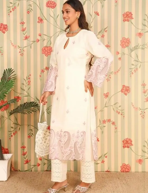 Aanchal in the ivory kurta set, side view, holding a potli bag